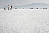 Parents pulling daughter in toboggan on snow, side view