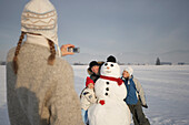 Familiy and snowman, mother photograhing