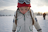 Mädchen 5-6 Jahre, mit roter Wollmütze steht in Winterlandschaft