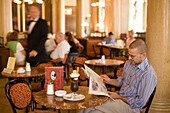 Man reading newspaper at Cafe Central, Vienna, Austria