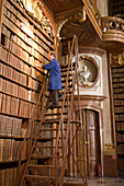 Man sorting books, standing on a ladder, Prunksaal of Nationalbibliothek National Libary, , Vienna, Austria