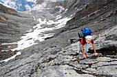 Young female alpinist climbing upon rock face, Piz Quattervals, Valetta, Swiss Nationalpark, Engadin, Graubuenden, Grisons, Switzerland, Alps