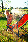 Little girl playing with garden hose