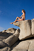 Woman on rock sunbathing, Costa Rei, Sardinia, Italy