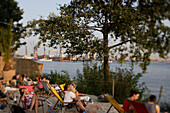 People sitting on deck chairs, beach club at river Elbe, St. Pauli, Altona, Hamburg, Germany