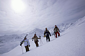 Snowboarder und Skifahrer laufen einen Berg hinauf, Kühtai, Tirol, Österreich
