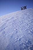Four persons on snowcovered mountain, arms raising high, Kuehtai, Tyrol, Austria