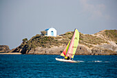 Catamaran passing Kastri island with capel St. Nicholas, Kefalos, Kos, Greece