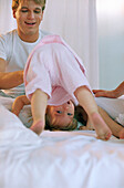 Female toddler doing somersault on bed