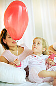 Toddler girl holding red balloon