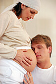 Mann hört am Bauch seiner schwangeren Frau