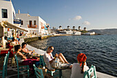 People sitting in restaurants and bars directly at sea, windmills in background, Little Venice, Mykonos-Town, Mykonos, Greece
