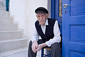 A local old man sitting in front of a white house, Mykonos-Town, Mykonos, Greece