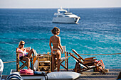 Women in the Goya Beach Bar, the only beach bar with pool, watching to a yacht at sea, Paranga Beach, Mykonos, Greece