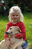 blond girl sitting in garden with dog Golden Retriever