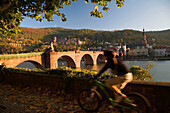 Biker in front of Neckar River and Karl Theodor Bridge, Heidelberg, Baden-Wuerttemberg, Germany