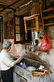 Hongkou quarter Shanghai, old lady cleaning vegetables, backstreet, communal wash basin, mirror, bamboo chair