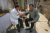 Hongkou quarter Shanghai, street doctor testing blood pressure