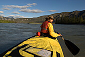 Mann beim paddeln am Nahanni Fluss blickt zurueck, Nordwestterritorien, Kanada