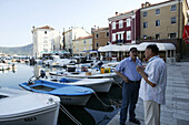 Men chatting on the pier, Cres Harbour, Cres Island, Croatia
