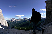 Hiker on the south slope of Tofana with Cernera and Formin Mountain in background, Veneto, Italy