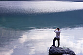 Man looking with binocular over Lake, Eibsee, Zugspitze in backround, Bavaria Germany
