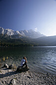 Man on shore of alpine lake with binoculars,lake eibsee, Zugspitze in back, Bavaria, Germany