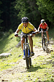 Two mountainbikers downhill on path with broken stones, Bavaria, Germany