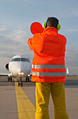 Airport ground crew signaling to aircraft, Airport Düsseldorf, North Rine-Westphalia, Germany