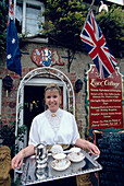 Waitress with tea tray in front of the Royal Essex Cafe in Godshill, Isle of Wight, England