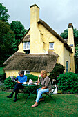 Ein Ehepaar, draußen vor einem Café in einem Strohgedecktes Landhaus, Selworthy, Somerset