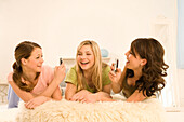 Teenage girls (14-16) on bed using mobil phones