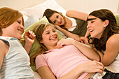 Teenage girls (14-16) on bed having fun