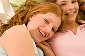 Two teenage girls (14-16) snuggling together on bed, close-up