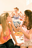 Teenage girls (14-16) applying make-up, girl with rollers in background