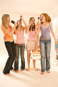 Teenage girls (14-16) singing into hair brushes