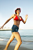 Young woman running on the beach, blurred motion