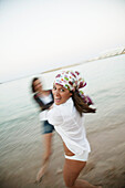 Two young woman holding hands and spinning on the beach, blurred motion