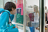 Young women looking at clothes in shop window