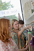 Young women looking at dresses on rack in a clothes shop