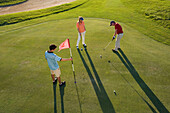 Golfers on golf course, long shadows
