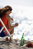Junge Frau liest im Liegestuhl am Strand, Apulien, Italien