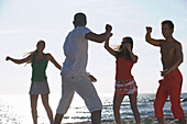Group of young people exercising on beach with instructor, Apulia, Italy