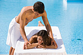 Young man massaging young woman on poolside, Apulia, Italy