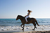 Junge Frau reitet am Strand, Apulien, Italien