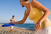 Junges Paar spielt Frisbee am Strand, Apulien, Italien