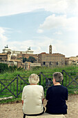 Two senior women sitting in front of Forum Romanum, Rome, Italy