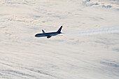 Aircraft with contrails above clouds