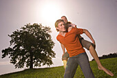 Man giving woman piggyback ride on grass