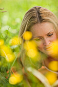 Young woman lying on meadow and reading book